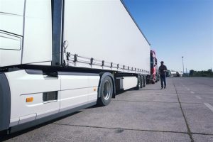 Professional truck driver inspecting a large white semitrailer at depot for expert fleet truck relocation services Australia