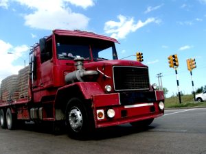 Red heavy-duty truck driving on road for commercial vehicle delivery services