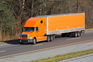 Orange semi-truck transporting cargo on a highway for interstate truck delivery