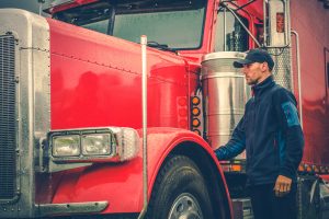 Truck operator standing beside a red heavy-duty vehicle during fleet relocation service