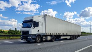 White freight truck driving on highway for reliable fleet delivery services